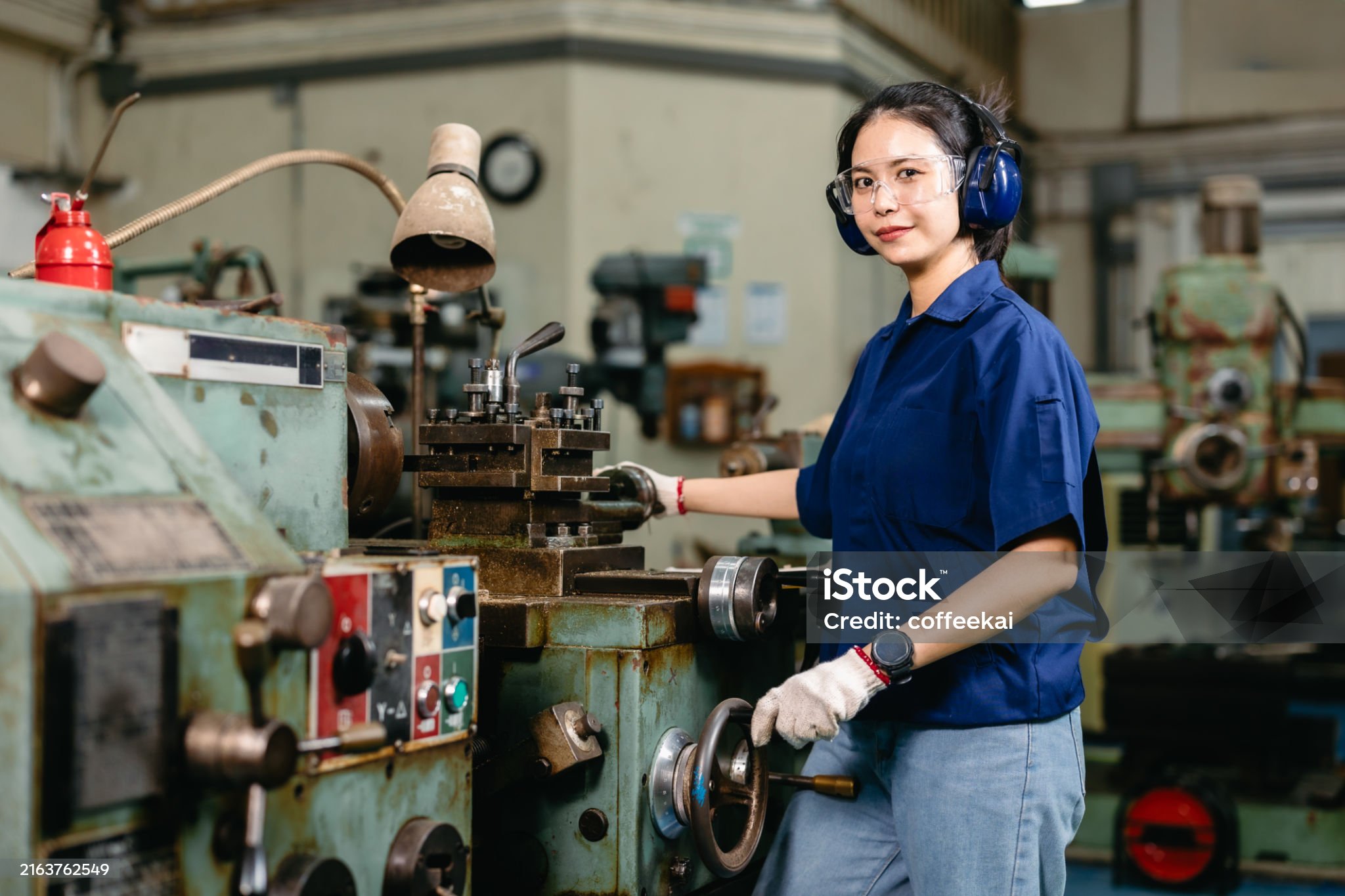 Portrait happy engineer worker with safety eyes protection glasses professional working with metal lathe milling machine heavy industry factory.